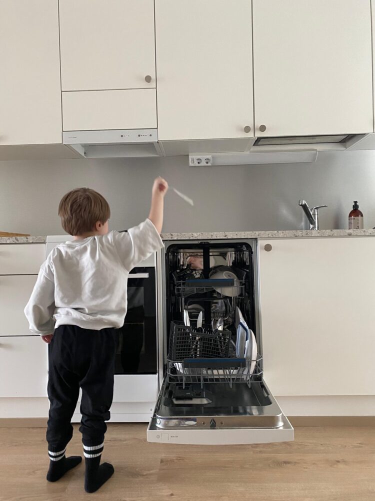 Poika täyttää tiskikonetta